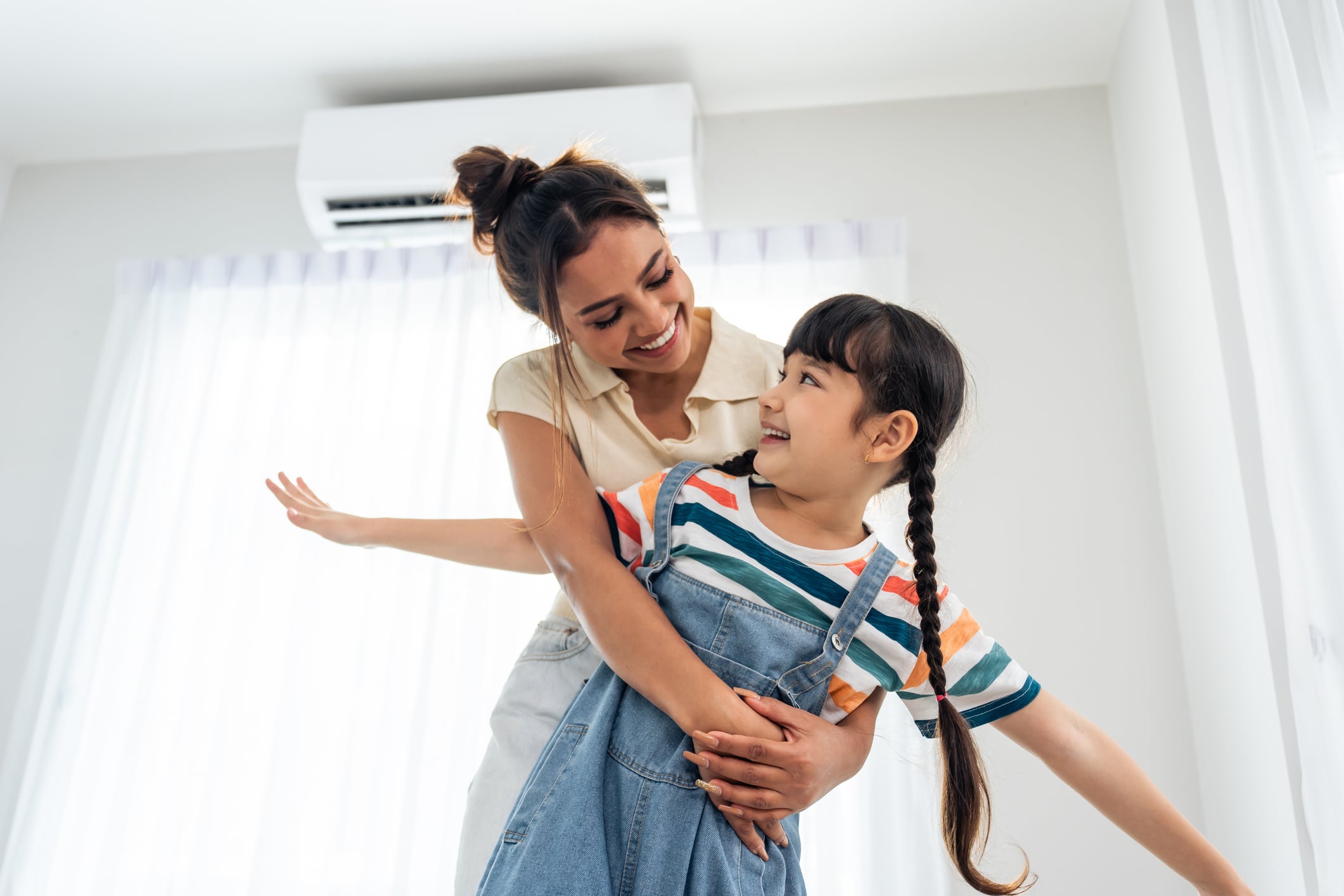 Caucasian happy family, parent spend free time with kid together at home. Adorable young girl daughter hug mother while playing with happiness in living room. Activity relationship in house concept.