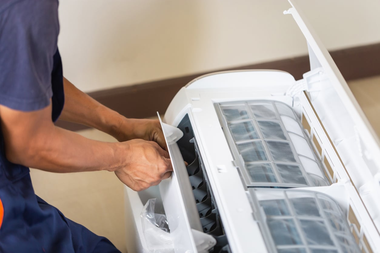 Technician man installing an air conditioning in a client house, Young repairman fixing air conditioner unit, Maintenance and repairing concepts