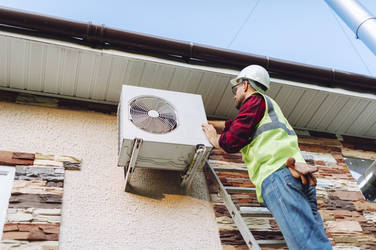 Technician in uniform repairing heat pump