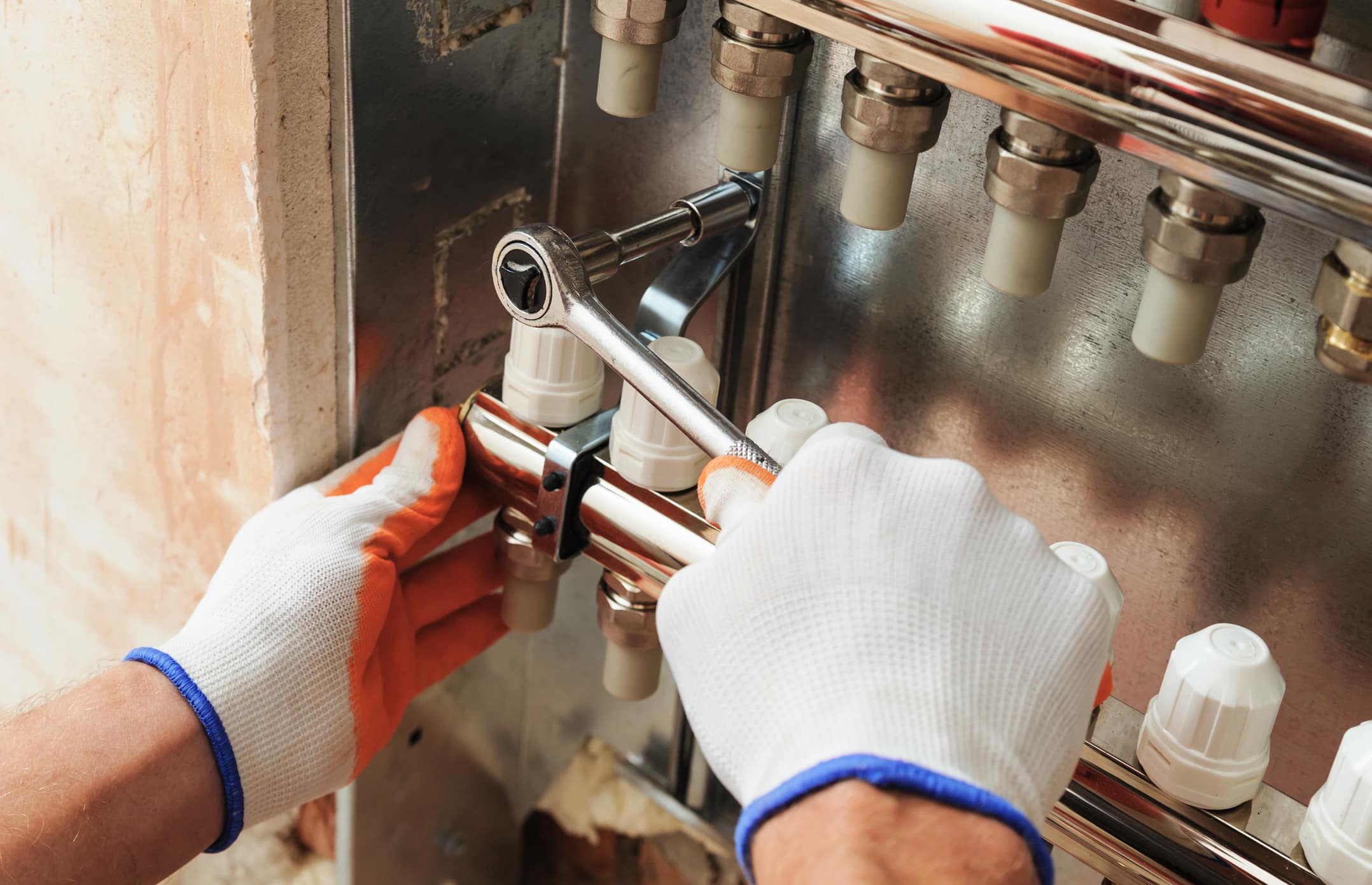 Installation of home heating. A worker fixes the underfloor heating manifold.